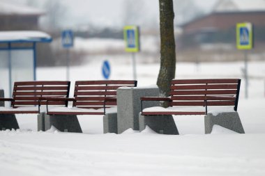 Dinlenmek için banklar kışın parkta karla kaplıdır.