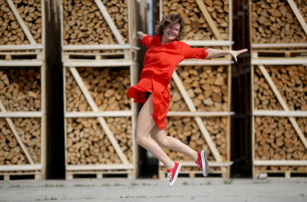 Jumping Schöne Frau Rotem Kleid Brennholz Backgroun — Stockfoto