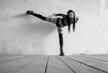 Fishnet kıyafetli gotik bir manken desenli beyaz bir duvara karşı anlamlı bir dans pozisyonu sergiliyor. Dinamik vücut dilini, dramatik duyguyu ve sanatsal performansı gösteren alternatif tarz hareket fotoğrafçılığı