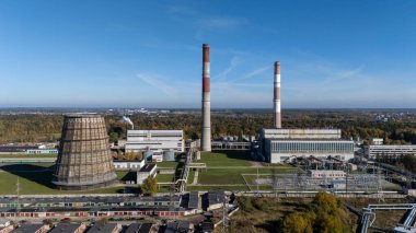 Litvanya 'daki Kaunas Termik Santrali' nin hava panoramik görüntüsü. Endüstriyel alanda bacalar, soğutma kulesi ve sonbahar ormanlarıyla çevrili enerji altyapısı yer alıyor..