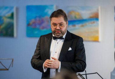 Opera sanatçısı Rafailas Karpis, 9 Şubat 2025 tarihinde Kedainiai Çok Kültürlü Merkezi 'nde verdiği canlı klasik müzik konserinde sahne aldı. Sanatçı resmi giyinmiş ve samimi bir kültürel ortamda şarkı söylüyor.