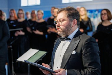 Opera sanatçısı Rafailas Karpis, 9 Şubat 2025 tarihinde Kedainiai Çok Kültürlü Merkezi 'nde verdiği canlı klasik müzik konserinde sahne aldı. Sanatçı resmi giyinmiş ve samimi bir kültürel ortamda şarkı söylüyor.