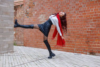 Dinamik portreler, arka planda tuğla bir sokakta dans eden bir kadının. Enerjik hareket, moda ayrıntıları ve açık havada doğal ışıkta yakalanan anlamlı hareket.