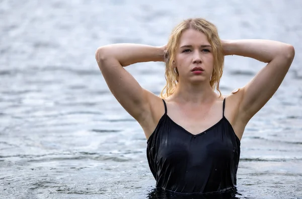 Siyah elbisesi dalgalanırken sakin suda zarif dans hareketleri yapan etkileyici genç bir kadın. Özgürlük kavramı, kadınlık, denge, duygusal ifade, beden farkındalığı ve doğa ile uyum.