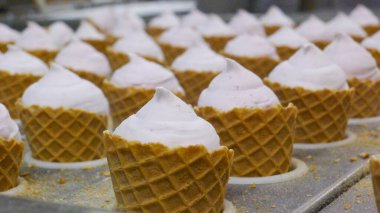 Endüstriyel dondurma külahı üretim hattı bir gıda fabrikasında. Otomatik makine waffle külahlarını yumuşak dondurmayla doldurur. Gıda üretimi, seri üretim, teknoloji ve işleme kavramı