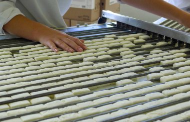 Bir gıda fabrikasında endüstriyel şeker üretim süreci. İşçiler toplu şekerleme imalatı sırasında konveyör bandında şeker sıralayıp şekillendiriyorlar. Gıda endüstrisi, kalite kontrol ve üretim hattı kavramı