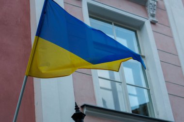 Ukrayna 'nın mavi ve sarı ulusal bayrağı bir Avrupa şehrindeki tarihi bir binanın cephesinde dalgalanıyor. Devam eden çatışmalar sırasında dayanışma, özgürlük, ulusal kimlik ve Ukrayna 'ya destek sembolü