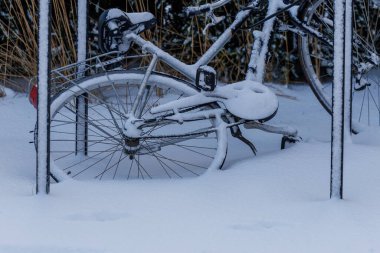 Kar kışın dışarıda park edilmiş bisikletle kaplıydı. Soğuk hava, taze kar ve sakin atmosferli kentsel kış manzarası. Doğal ışık ve mevsimsel arkaplan içeren minimum bileşim