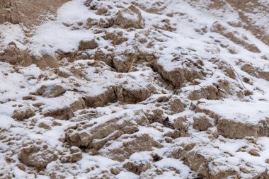 Taze karla kaplı aşınmış kum kayalıklarına yakın çekim. Doğal kış dokusu katmanlar, çatlaklar ve rüzgar ve hava tarafından şekillendirilen kırılgan yüzeyleri gösteriyor. Soyut arkaplan, jeoloji ve iklim kavramı.