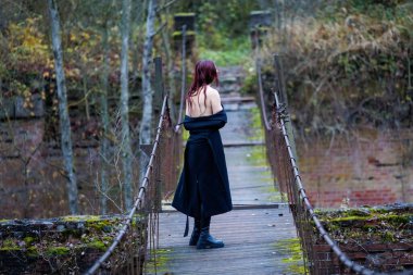 Açık havada dar bir yaya köprüsünde duran genç bir kadının sanatsal çıplak portresi. Duruş sakin ve asgari, vurgulu biçim, denge ve insan vücudu ile doğa arasındaki bağlantı. Kavramsal sanat fotoğrafçılığıyla