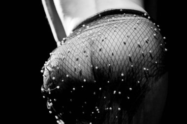 Siyah beyaz güzel sanatlar stüdyosu fotoğrafında soyut bir kadın vücut detayı var. Örgü kumaş ve inci süslemelerle kaplı. Doku, biçim, ışık ve gölge, moda estetiği ve minimalist kompozisyon üzerinde duruluyor. Kavramsal resim suita