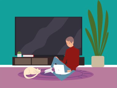 Dizüstü bilgisayarı olan genç adam yerde oturmuş çalışıyor.