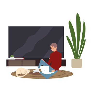 Genç adam oturma odasındaki halıda dizüstü bilgisayarla çalışıyor.