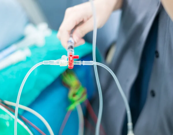 Arzt schiebt medizinische Lösung in intravenöse Flüssigkeitsleitung — Stockfoto