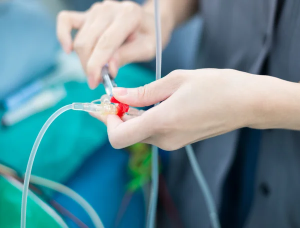 Médico empurrar solução médica em linha de fluido intravenoso — Fotografia de Stock