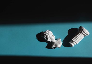 Sert bir ışığın altında yerde yatan bir kadının eski bir büstünün kırık kopyası.