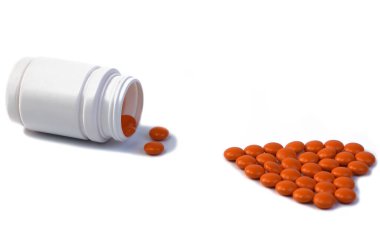 Turuncu haplı bir şişe beyaz arka planda yatar, haplar kalp şeklinde düzenlenir, fikir, konsept, izole