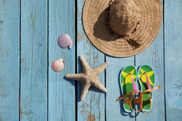 Şapka, sandal, deniz kabuklarını ve denizyıldızı mavi zemin üzerine.