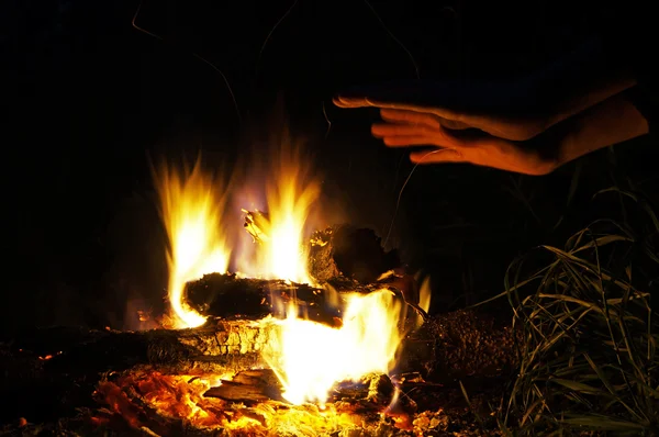 A man warms his hands at the fire. — Stock Photo, Image