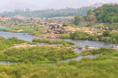 Hampi Köyü Tungabhadra nehir çayır. Manzara su, palm, rock, taşlar ile. Türkiye, İstanbul