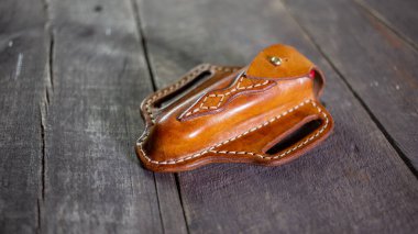 Tahta arka planda el yapımı deri krep İsviçre çakısı kılıfı. Elle dikiş..