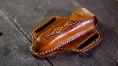 Tahta arka planda el yapımı deri krep İsviçre çakısı kılıfı. Elle dikiş..