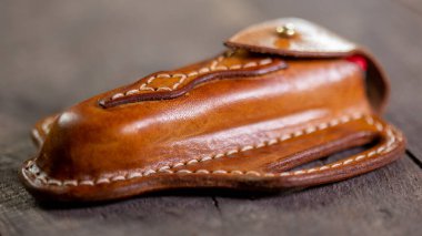 Tahta arka planda el yapımı deri krep İsviçre çakısı kılıfı. Elle dikiş..