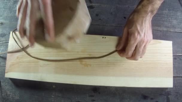 Skórzana koronka procesu ręcznie. Lina toczy się po drewnie. Domowej roboty. Drewno tło skóra produkcja z męski ręka. 4k, 30 klatek na sekundę. — Wideo stockowe