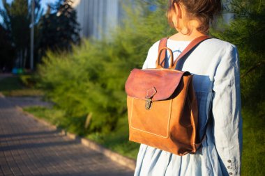 Kız deri el yapımı çanta giyiyor. Deri sırt çantası ürünü.