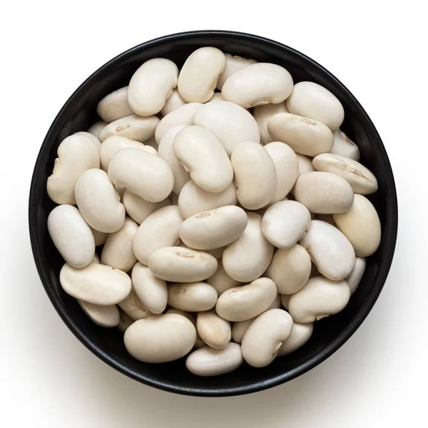 白色的豆子在一个黑色陶瓷碗中 与白色隔离 顶部视图 — 图库照片
