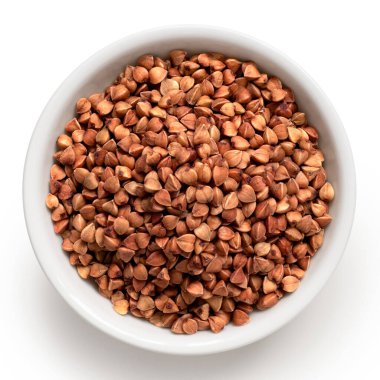 Beyazda izole edilmiş beyaz bir seramik kasede çiğ karabuğday. Üst görünüm.