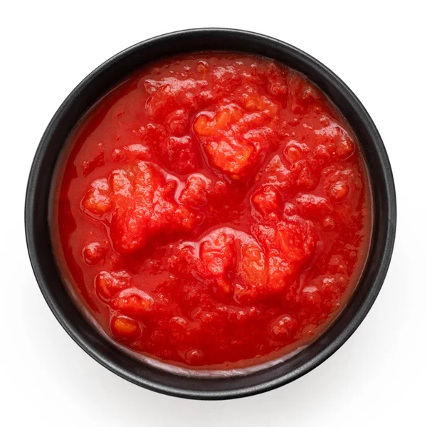 白に隔離された黒い陶器のボウルにトマトをみじん切りにした缶詰 トップ表示 — ストック写真