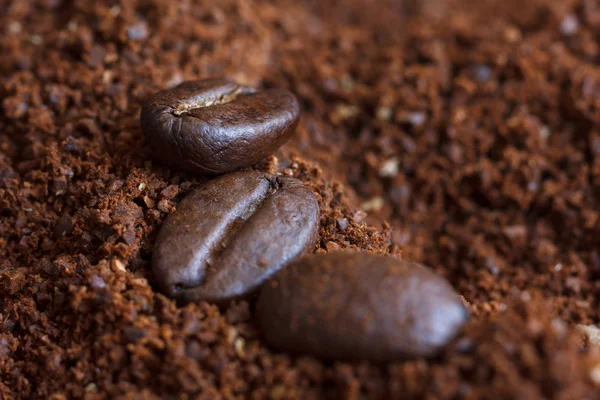 Gebrande koffiebonen op gemalen koffie. — Stockfoto