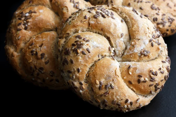 Whole wheat kaiser rolls with sesame seeds on black surface. — Stock Photo, Image