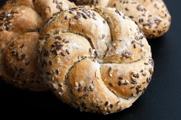 Whole wheat kaiser rolls with sesame seeds on black surface. — Stock Photo, Image