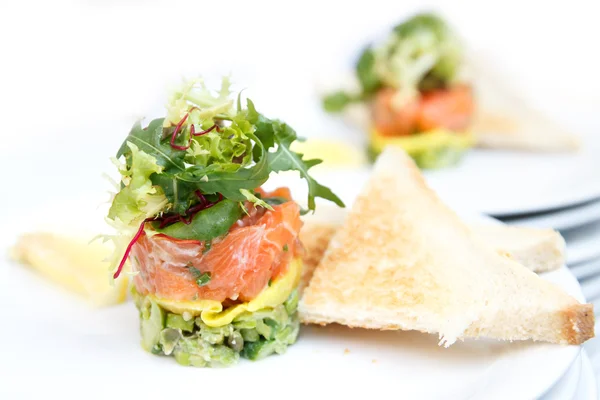 Tártaro de salmón y aguacate con tostadas y limón . —  Fotos de Stock