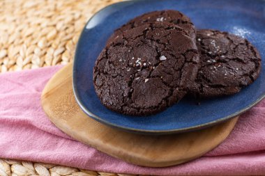 Lezzetli çifte çikolatalı kurabiyeler, mavi tabakta deniz tuzu.