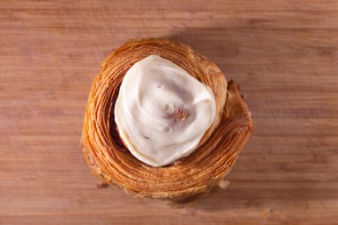 Tarçınlı çörek, tereyağlı kruvasan hamuru ve ahşap kesim tahtasındaki krem peynirli krema.