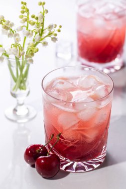 Yaz güneşinde kirazlı ve çiçekli iki güzel vişneli kokteyl.