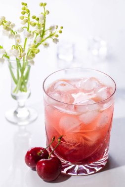 Yaz güneşinde kirazlı ve çiçekli güzel kırmızı kiraz kokteyli.
