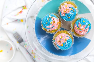 Parlak, mavi ve pembe kapkekler, beyaz bir mutfakta serpiştirilmiş.