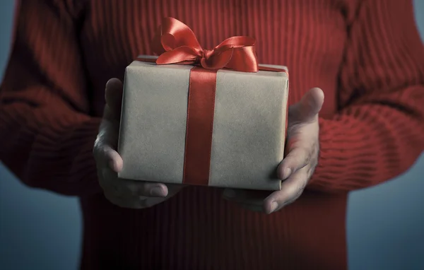 Männerhände mit roter Schleife Geschenkbox. — Stockfoto