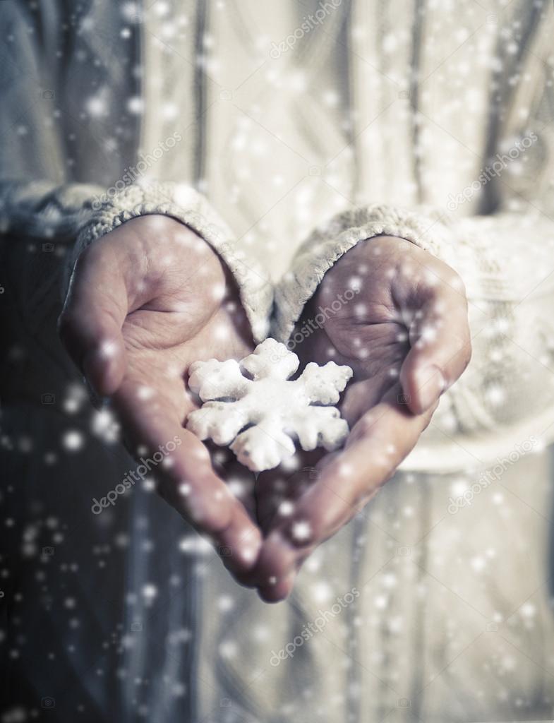  Hands holding a snowflake. 