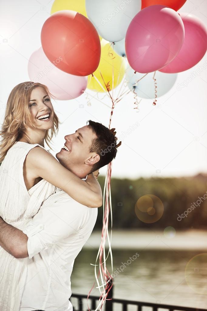 Young happy couple holding colorful ballons and embracing.