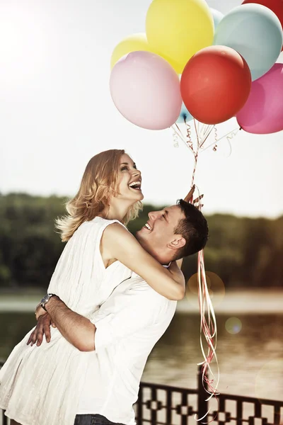 Joven atractiva feliz pareja con coloridos globos abrazando un — Foto de Stock