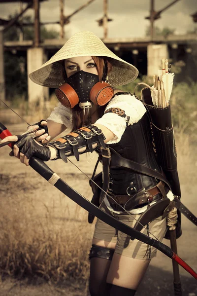 Attractive woman warrior in the mask holding in her hands bow an — Stock Photo, Image