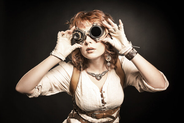 Beautiful redhair steampunk girl looking over her goggles aside 