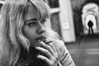 Şiddete Karşı Kavram. Korkmuş, gergin, sigara içen bir kadın karanlık bir sokakta şüpheli bir adamın siluetinin önünde dikiliyor..