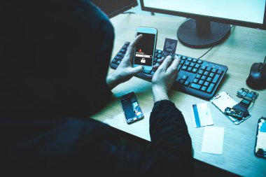 Erkek hacker telefona erişmeye çalışıyor. Kişisel verilerin güvenliği ve korunması. Siber suçlar ve elektronik cihazları hackleme kavramı