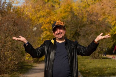 Siyah ceketli neşeli, tombul bir adam sonbaharın gelişinin keyfini çıkarıyor..